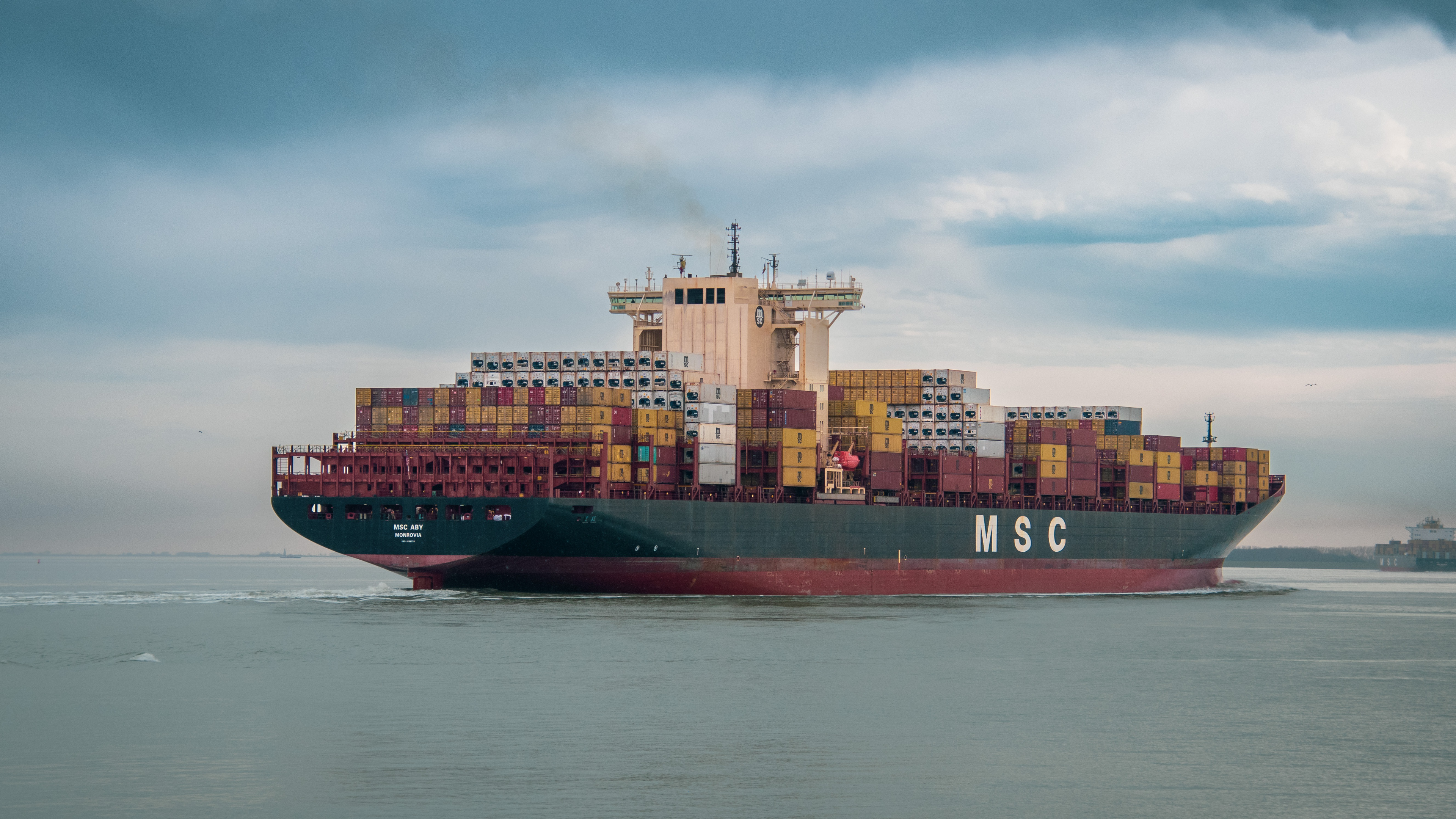 Container ship being guided into port by tugboats